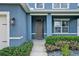 Front entrance features a dark door with sidelight, surrounded by manicured greenery and landscape at 5967 Churchill Square Way, Groveland, FL 34736