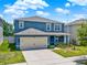 Beautiful two-story home with blue siding, a two-car garage, and a green, well-maintained lawn at 5967 Churchill Square Way, Groveland, FL 34736