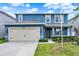 Inviting two-story home with blue exterior, a two-car garage, and manicured front yard landscaping at 5967 Churchill Square Way, Groveland, FL 34736
