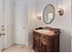 Charming powder room featuring a wood vanity, oval mirror, and sconce lighting at 6161 Blakeford Dr, Windermere, FL 34786