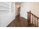 Inviting hallway featuring hardwood floors, built-in bookshelves, and a staircase with wooden banister at 6161 Blakeford Dr, Windermere, FL 34786