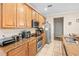 Well-equipped kitchen featuring warm wood cabinetry, granite countertops, stainless appliances, and tile flooring at 6205 Miramonte Dr # 103, Orlando, FL 32835