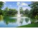 Picturesque lake view featuring a grand fountain surrounded by lush greenery and clear blue skies at 6205 Miramonte Dr # 103, Orlando, FL 32835