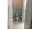 Cozy bathroom with white toilet, gray walls, white tiled floor, towel bar, and white baseboards at 6304 Raleigh St # 204, Orlando, FL 32835