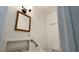 Compact bathroom features a wood framed mirror, light fixture, and grab bar at 714 Herbert St, Port Orange, FL 32129
