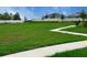 Green space with walking path, bench, and view of houses with solar panels in a fenced community at 734 Ginger Dr, Haines City, FL 33844