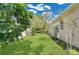 Backyard with lush green grass, garden beds, and a beige single-story home at 7900 Saint Giles Pl, Orlando, FL 32835