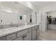 A full bathroom with double sink vanity, granite countertops, white cabinets, tile flooring, and a walk-in closet at 850 Lazio Cir, Debary, FL 32713