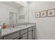 Modern bathroom featuring double sinks, granite countertops, and a large mirror framed with stylish baby pictures at 850 Lazio Cir, Debary, FL 32713