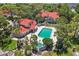 Aerial view showcasing a complex with a pool, mature trees, well-manicured landscaping, and red tile roofs at 935 Northern Dancer Way # 107, Casselberry, FL 32707