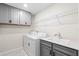 Practical laundry room includes washer, dryer, sink and gray cabinets for storage solutions at 10245 Park Estates Ave, Orlando, FL 32836