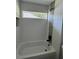 Bathroom featuring white tiling, horizontal window, mosaic tiling accent, and tub with black fixtures at 10641 Sw 110Th Ct, Dunnellon, FL 34432