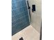 Modern shower featuring blue vertical tiles, gray floor and wall tiles, and a sleek black shower head at 10641 Sw 110Th Ct, Dunnellon, FL 34432