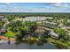 Aerial view of a lakeside home with a dock, trees, and a nearby road, creating a serene and accessible setting at 11 Plumosa Ave, Casselberry, FL 32707