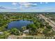 An aerial view of a neighborhood and a lake surrounded by lush green trees, homes, and a winding road at 11 Plumosa Ave, Casselberry, FL 32707