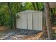 A simple metal outdoor storage shed situated in a backyard with trees and natural surroundings at 11 Plumosa Ave, Casselberry, FL 32707