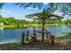 Picturesque lake view featuring a unique rustic picnic table under a clear blue sky at 11 Plumosa Ave, Casselberry, FL 32707