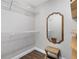 Bright walk-in closet with wooden floors, ample shelving, stylish mirror and decorative woven bench at 1172 Trotwood Blvd, Winter Springs, FL 32708