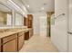 Bathroom featuring double sinks, wood cabinets, tile floors, granite countertops, and view of tiled shower at 14078 Alafaya Oak Bnd, Orlando, FL 32828