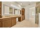 Bathroom featuring double sinks, wood cabinets, tile floors, granite countertops, and view of tiled shower at 14078 Alafaya Oak Bnd, Orlando, FL 32828