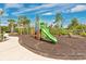 A colorful playground featuring a slide amidst landscaping on a mulch bed at 14078 Alafaya Oak Bnd, Orlando, FL 32828
