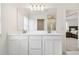 Elegant bathroom with double sinks, white cabinetry, a large mirror, and bright lighting at 14655 Erice Ave, Clermont, FL 34714