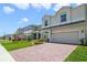 Charming two-story home boasts a well-manicured lawn and a brick driveway leading to a two-car garage at 14655 Erice Ave, Clermont, FL 34714