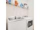 A laundry room is equipped with a GE washer and dryer, alongside shelving for supplies at 14655 Erice Ave, Clermont, FL 34714