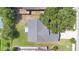 Aerial top-down view of a property showcasing its roof, yard, driveway, and surrounding mature trees in a sunny setting at 1614 Christa Ct, St Cloud, FL 34772
