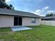 Grassy backyard featuring a patio, sliding glass doors, and mature landscaping, providing a serene outdoor space at 1614 Christa Ct, St Cloud, FL 34772