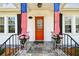 View of front porch decorated with American flags and planters with pink flowers at 2505 Amherst Ave, Orlando, FL 32804