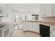 Bright kitchen with white cabinets, appliances, and tile flooring, leading to a sunlit nook at 2506 Aster Cove Ln, Kissimmee, FL 34758