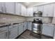 Updated kitchen features stainless steel appliances, granite countertops, gray cabinets, and modern backsplash at 3422 Heath Dr, Deltona, FL 32725