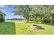 Expansive backyard featuring lush green grass, mature trees, and a stone fire pit at 4394 Devon Ct, Kissimmee, FL 34746