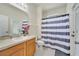 Traditional bathroom with a wood vanity, neutral countertops, and a shower featuring a blue and white curtain at 4394 Devon Ct, Kissimmee, FL 34746