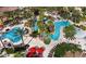 Aerial view of a resort-style pool area with palm trees, lounge chairs, and red umbrellas at 528 Terra Lago St, Davenport, FL 33897