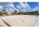 Sand volleyball court with blue trim, a Tiki bar and building exteriors under a partly cloudy sky at 528 Terra Lago St, Davenport, FL 33897
