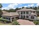 Elegant two-story home with a tile roof, brick driveway, manicured landscaping, and a three-car garage at 5683 Bassett Pl, Sanford, FL 32771