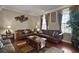 Comfortable living room featuring hardwood floors, leather furniture, decorative curtains, and stylish decor at 5683 Bassett Pl, Sanford, FL 32771