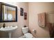 Chic powder room with decorative mirror, pedestal sink, toilet, and wall art, exuding style and comfort at 5683 Bassett Pl, Sanford, FL 32771