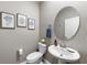 A stylish half bath with pedestal sink, round mirror, and attractive decor at 816 Carmillion Ct, Groveland, FL 34736