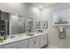 A bright bathroom featuring double sinks, a large mirror, and modern fixtures at 816 Carmillion Ct, Groveland, FL 34736