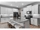 Modern kitchen featuring a large center island with seating, white cabinetry, and stainless steel appliances at 816 Carmillion Ct, Groveland, FL 34736