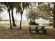 Scenic lake view picnic area with mature trees and weathered picnic table at 816 Carmillion Ct, Groveland, FL 34736