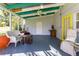 Relaxing covered patio with seating area, ceiling fan and bright yellow door at 11 S University Cir, Deland, FL 32724
