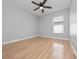 A bright bedroom featuring wood laminate floors, a ceiling fan, and a window that allows plenty of natural light at 11218 Rouse Run Cir, Orlando, FL 32817