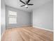 A bright, empty bedroom features wood laminate flooring, a ceiling fan, and a window that allows natural light to fill the space at 11218 Rouse Run Cir, Orlando, FL 32817