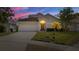 Charming single-story home with a well-manicured lawn and attached two-car garage at dusk at 11218 Rouse Run Cir, Orlando, FL 32817