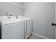 A well-equipped laundry room featuring a white washer and dryer, and a wire shelf for storage at 11218 Rouse Run Cir, Orlando, FL 32817