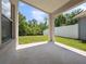 An empty outdoor patio with a concrete floor offers views of a lush, green backyard and a white fence at 11218 Rouse Run Cir, Orlando, FL 32817